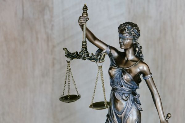 Figur Justitia hebt mit verbundnen Augen eine Waage in ihrer rechten Hand